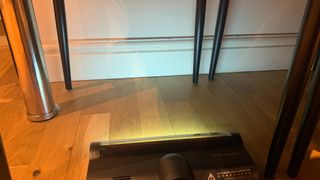 Roidmi X300 with its light-sensitive floorhead beam on, vacuuming under a table