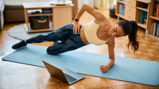 Woman performs side plank leg lift exercise at home