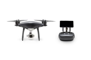 The matte-gray Phantom 4 Pro Obsidian drone and its matching controller sitting stationary against a white background