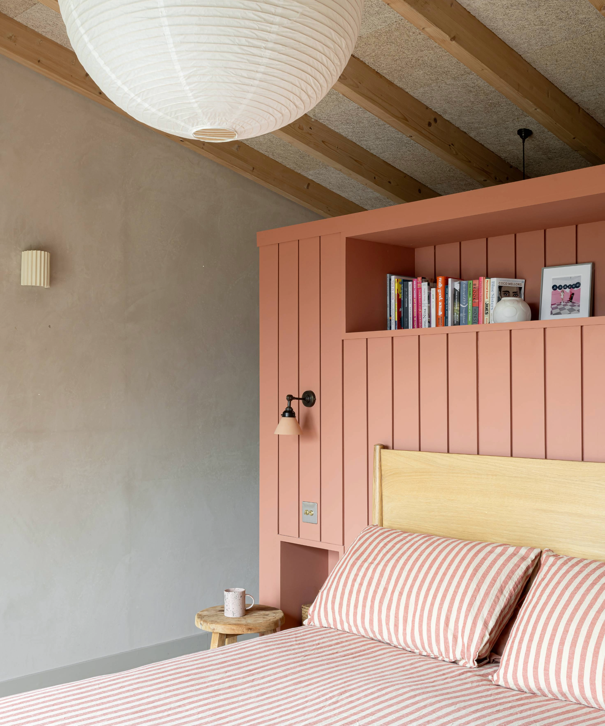 Bedroom with salmon headboard with built-in bookcase and stripy duvet cover