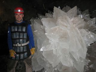 Wearing an ice-pack vest, Mario Corsalini stands by a giant rosette of gypsum in the Naica Mine's crystal cavern.