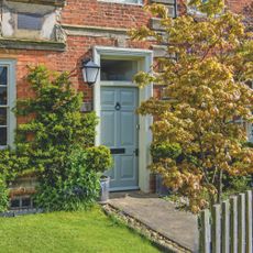 Front garden with wall-climbing plants, ornamental tree, garden path, small lawn area and bench