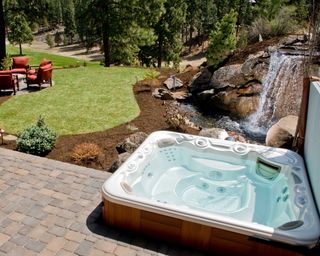 hot tub in landscaped garden with waterfall