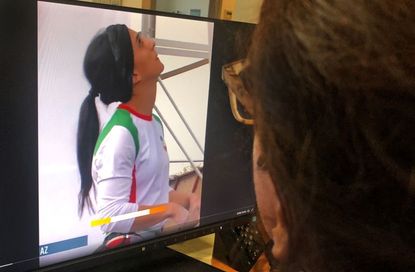 Woman looking at Rekabi on monitor without hijab