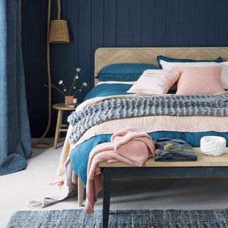 A navy bedroom with a wooden bed and pink accessories