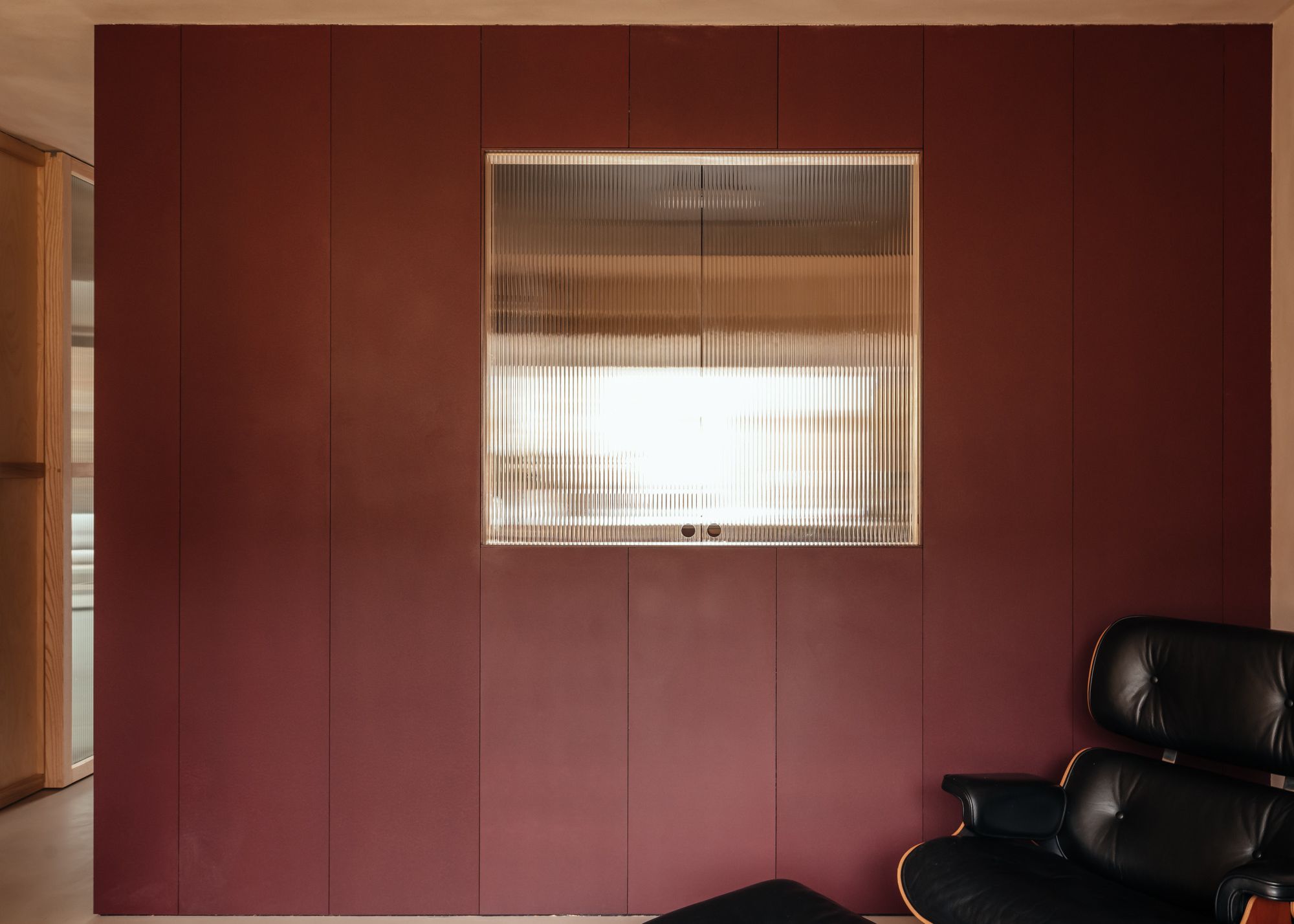 A kitchen painted red, with a hatch in reeded glass
