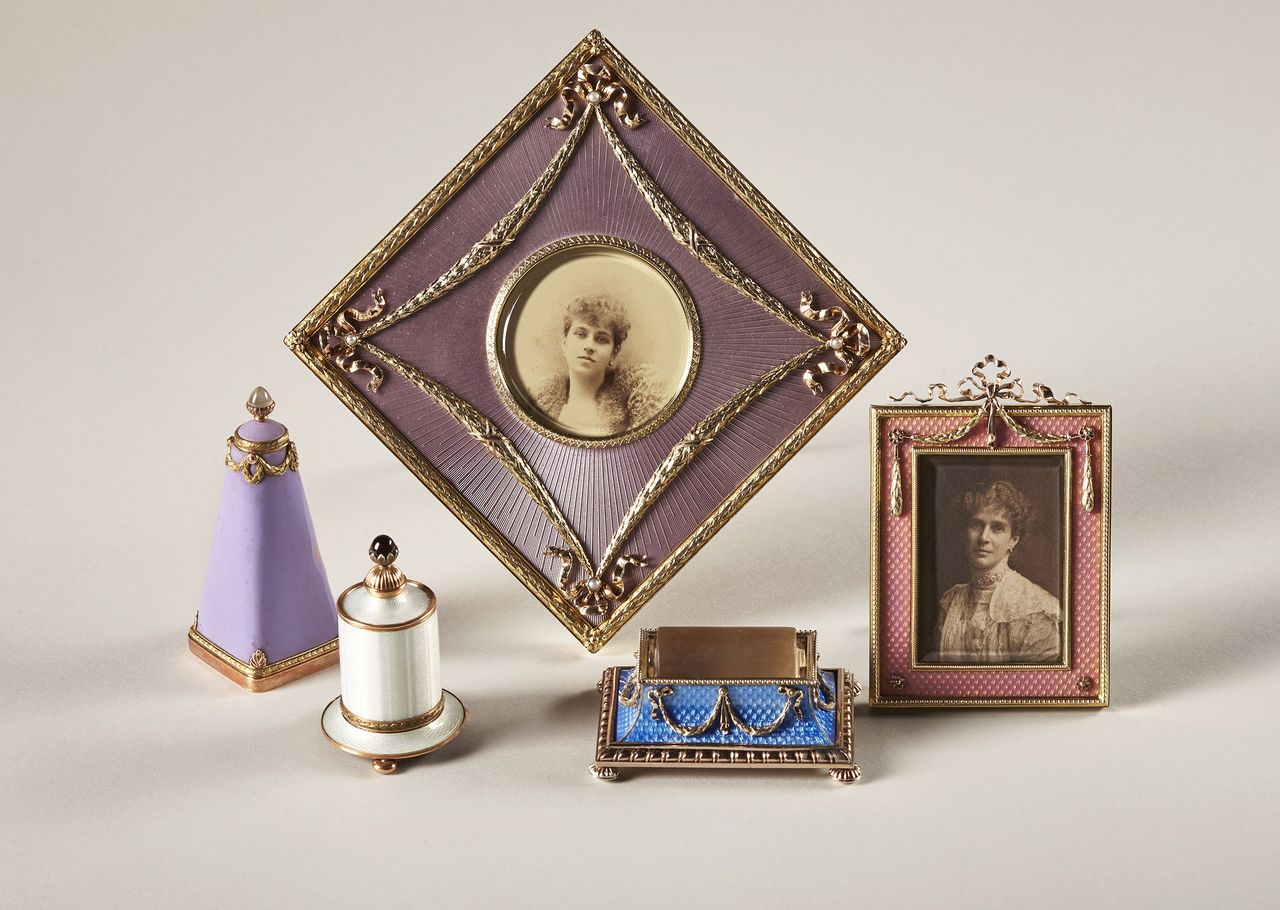 The Fabergé objects from the collection of Brighton and Hove Museum. The two gold-mounted table frames are decorated with rose-pink enamels and applied with lovers knots and laurel leaves emblematic of the Triumph of Love. The identity of the women in the pictures remains an enigma. The three objets de luxe are decorated with translucent and matt enamels. The stamp damper is made of silver-gilt and the roller is carved from rock crystal. The gold-mounted gum pots are applied with trails of triumphal laurels and the brush handles set with a cabochon garnet and a moonstone.