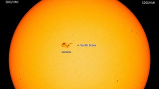 A zoomed out image of the sunspot next to Earth for size comparison