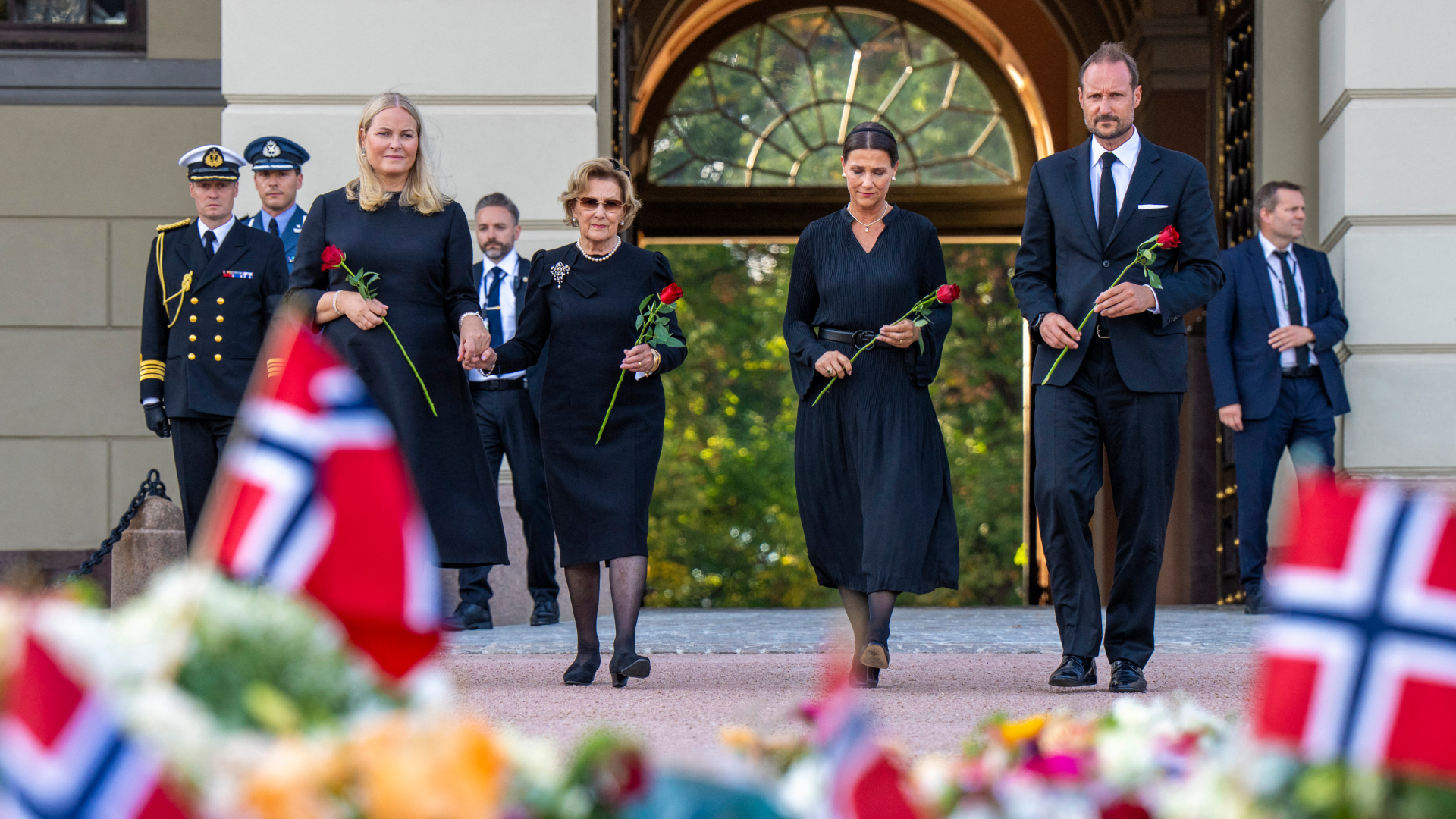 Queen Mette-Marit , Queen Sonja, Princess Martha Louise and King Haakon wearing black outfits holding roses