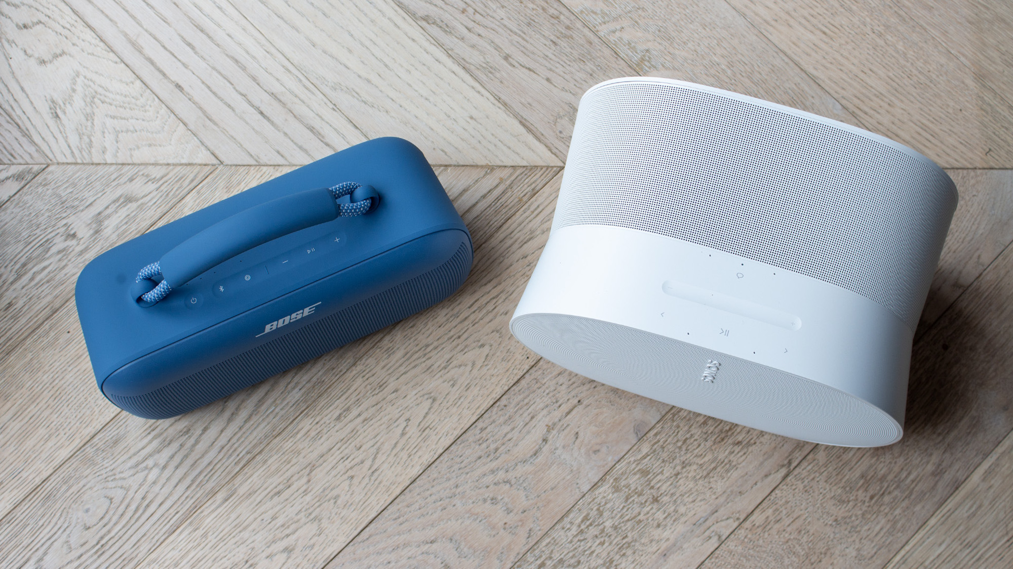 A side-by-side view of a blue Sonos Era 300 and a white Bose SoundLink Max.