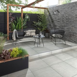 Grey patio with square paving stones, black table and chairs