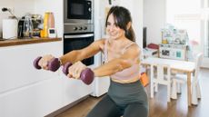 woman works out with dumbbells in her kitchen