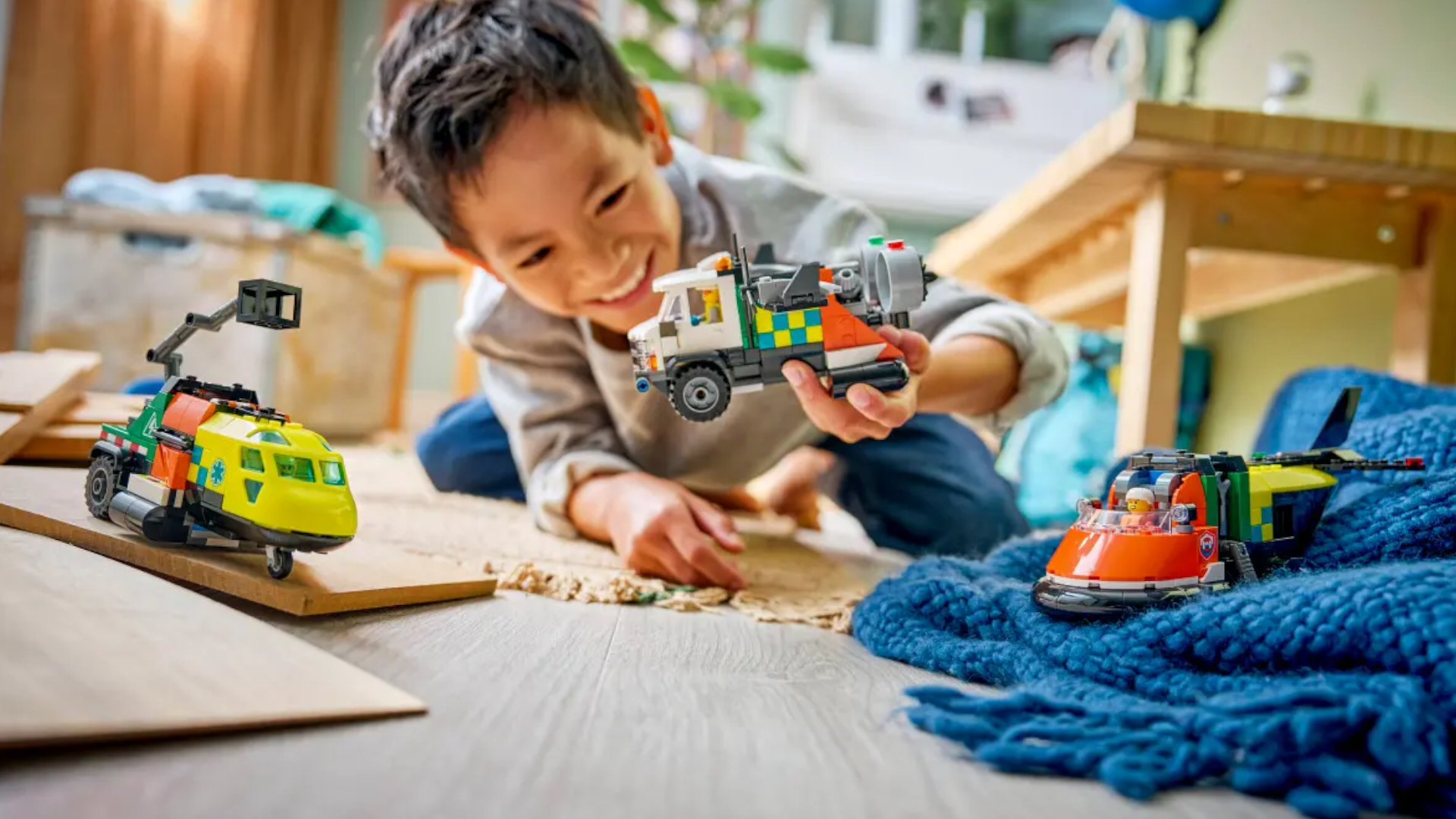A child plays with the Lego Airplane, Service Truck, & Hovercraft set on the floor