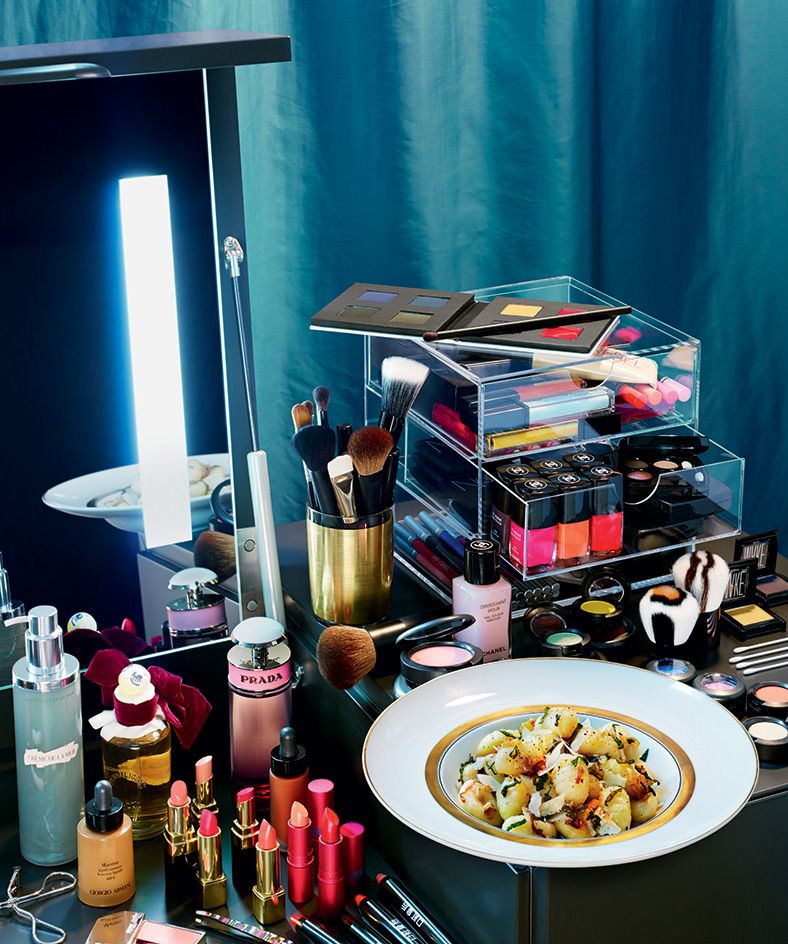 Plate of food on a table with make up products displayed around it