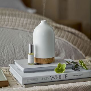 an electronic diffuser sitting on a pile of books with a small bottle of scented oil