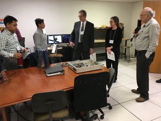 The SPACE HAUC team describing their project to distinguished visitors. From left, undergraduate students Simthyrearch Dy, project manager, and Sanjeev Mehta, communication systems lead. The visitors include James Green, NASA chief scientist, Megan Donahue and Bob Twiggs, inventor of CubeSat.