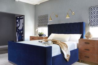 blue and gray bedroom, blue velvet bed, gray textured wallpaper, artwork, wooden side table, blends, carpet