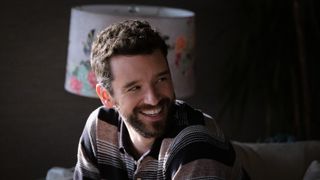 Michael Urie as Brian, sitting in front of a floral lamp, in 'Shrinking'