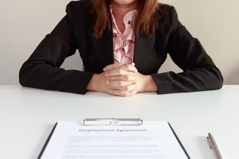 A woman sits in front of a contract with a job offer.