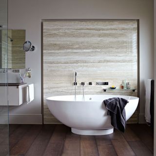 bathroom with marble wall and bathtub and wooden floor