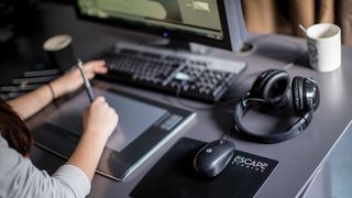 Digital artist drawing on a tablet at a desk