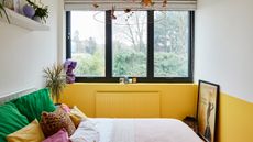 Bedroom with yellow and white colour block wall, black steel windows