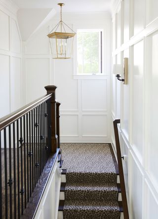 white paneled staircase and landing with leopard print runner and black banisters