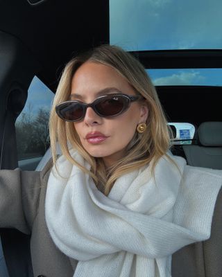 Woman in scarf, sunglasses, and gold round earrings.