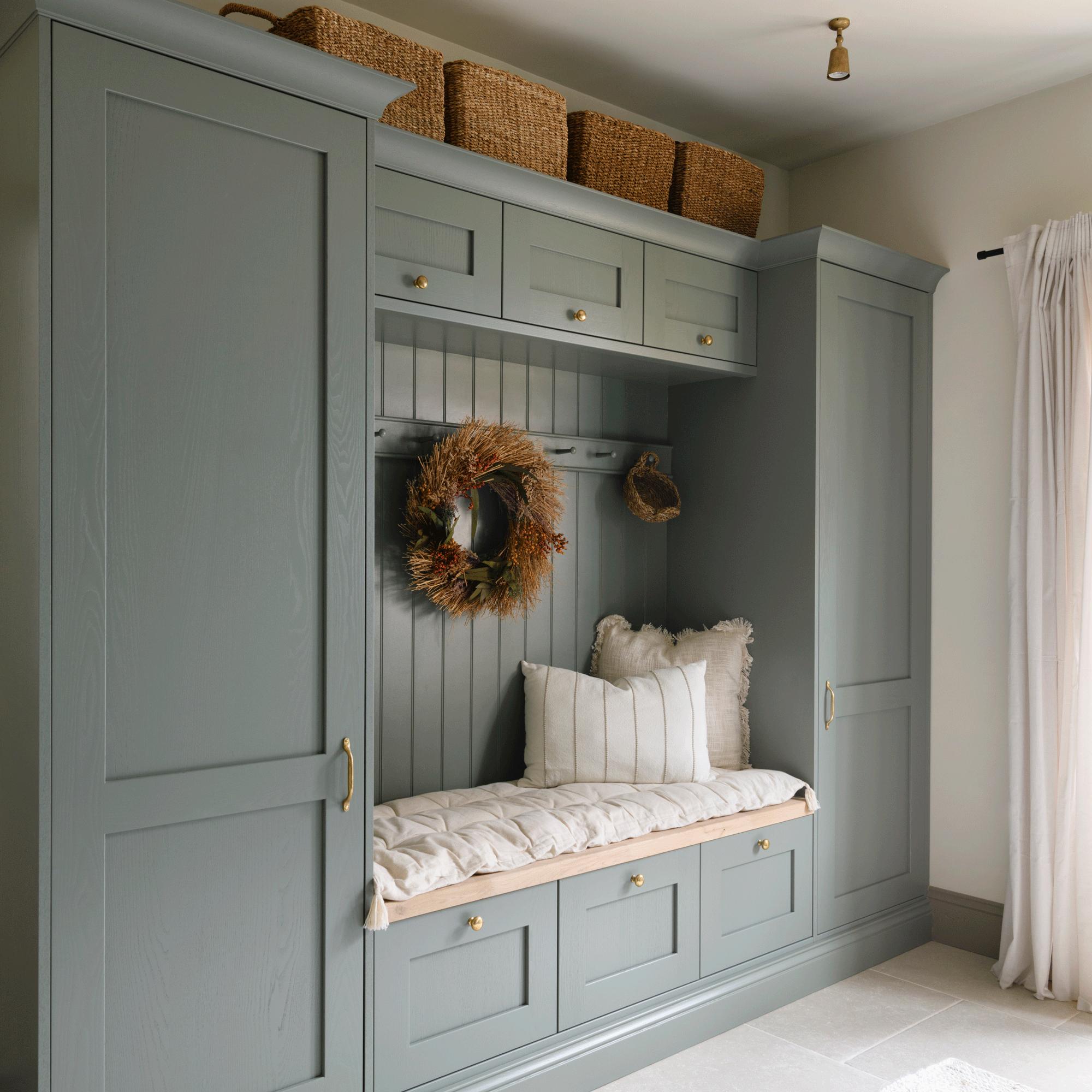 a utility room with fitted cabinets and a bench area with peg rail and cushions