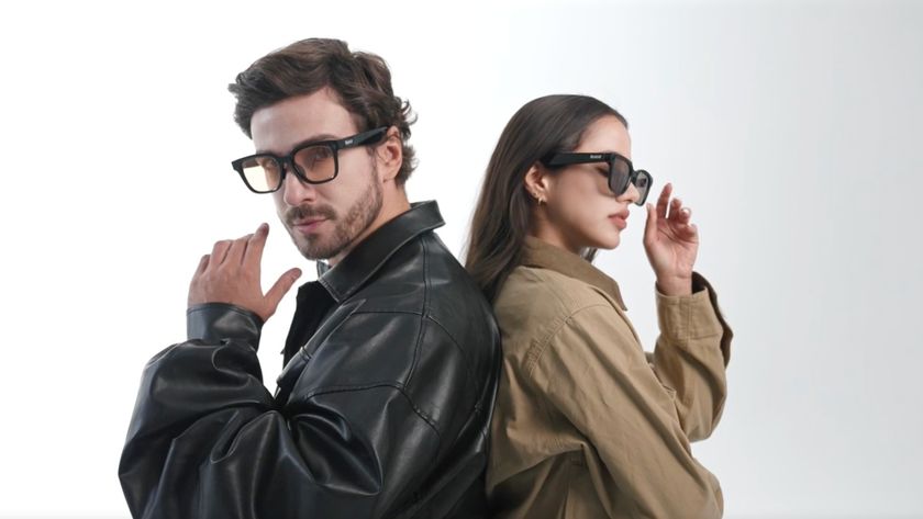 A man in a black leather jacket and a woman in a tan jacket stand back-to-back while wearing stylish Rokid smart glasses.