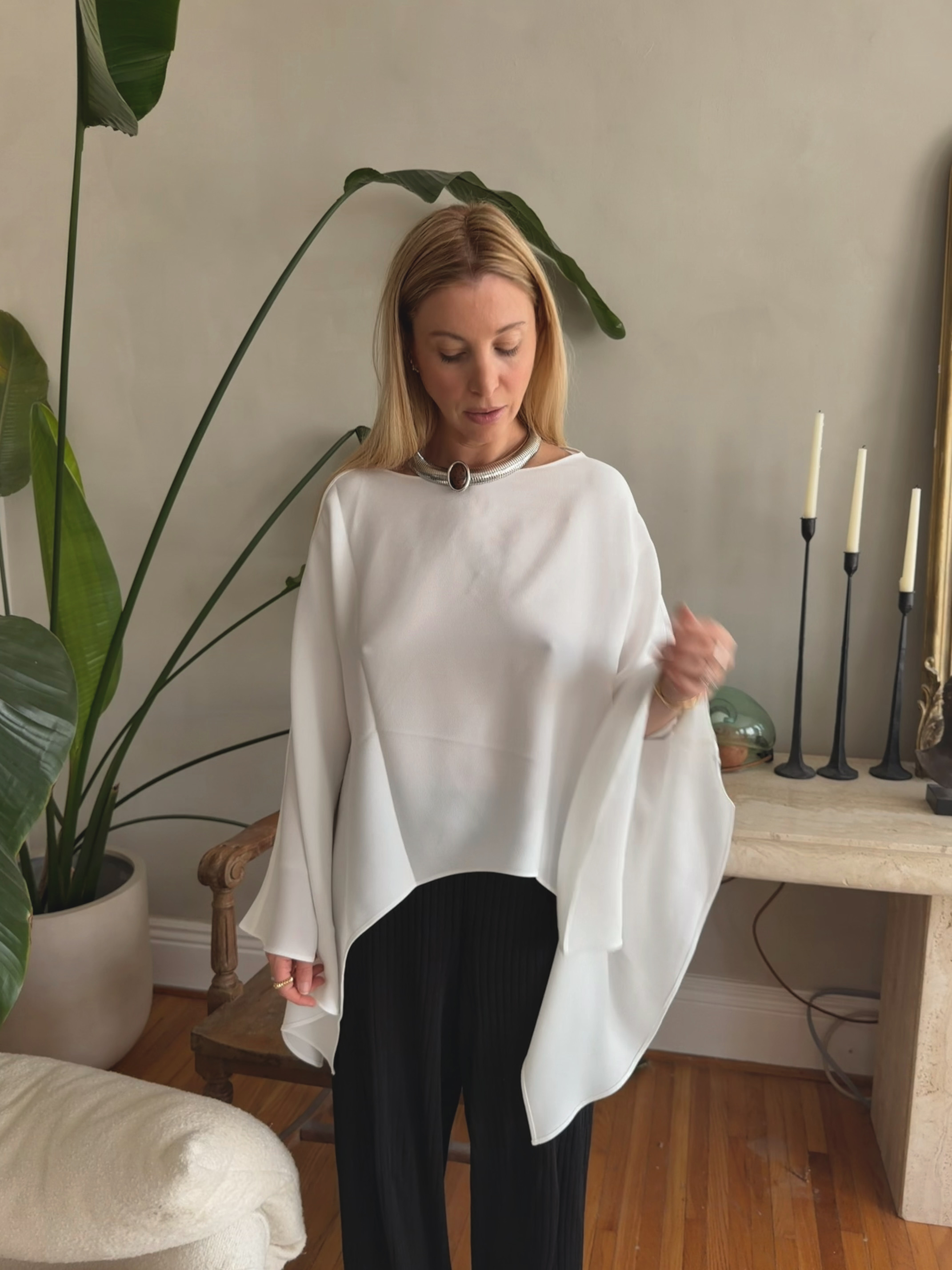 Kerry Pieri wearing a white tunic, black pants, and silver chain with a brown stone necklace