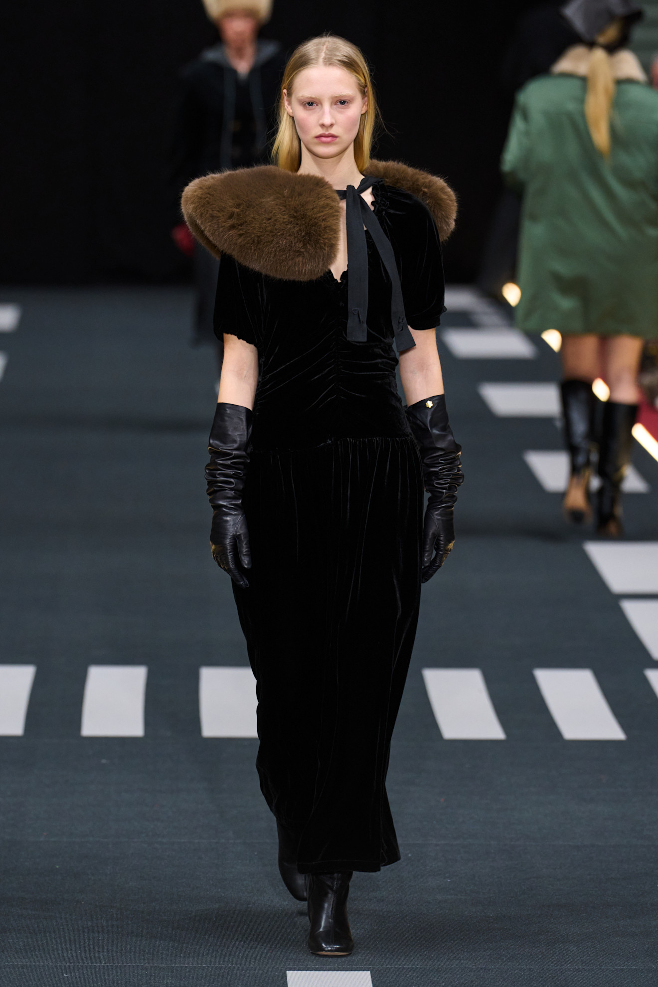 a model on the Baum und Pferdgarten runway wearing a fur collar over her velvet dress