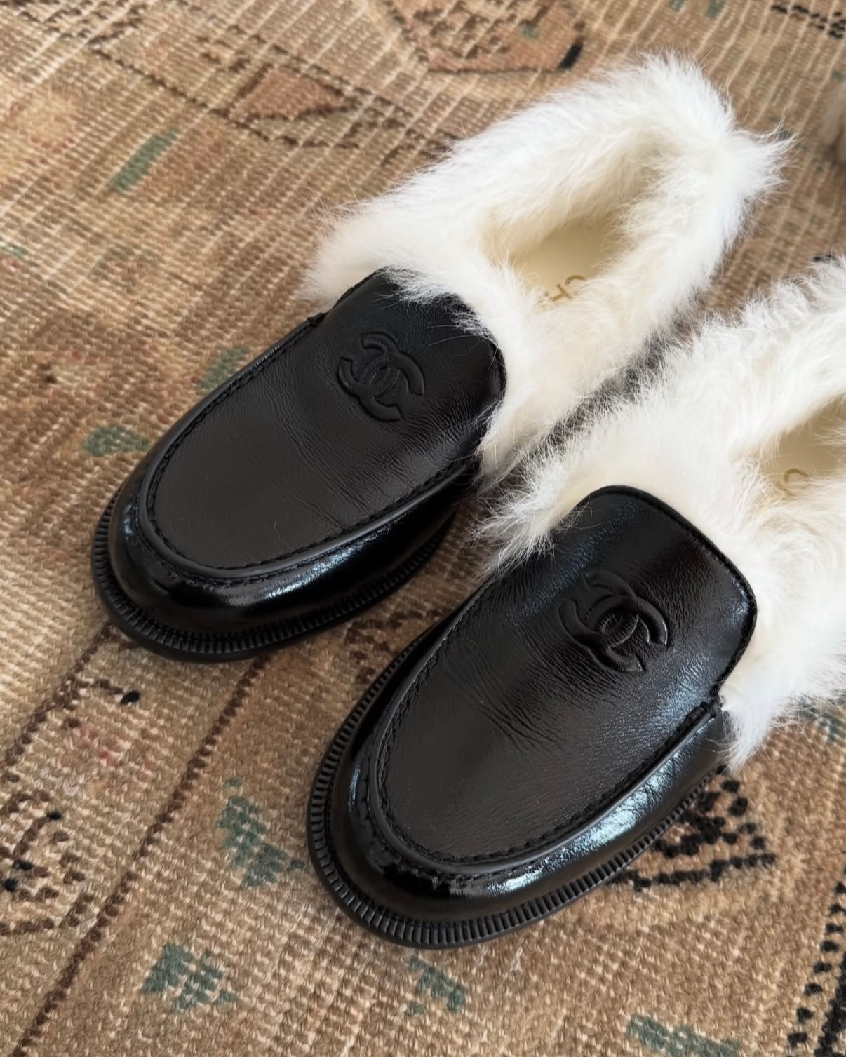 @ingridedvinsen showcases a pair of black leather shearling-lined loafers from Chanel on a tapestry rug