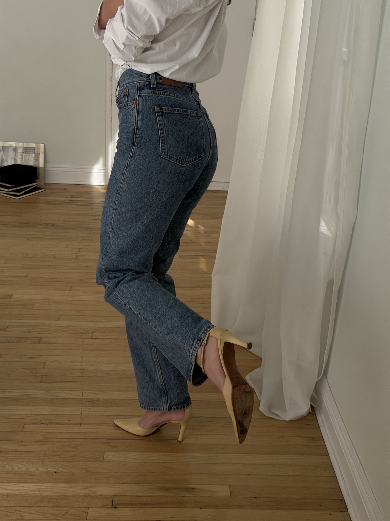 Kathryn Zahorak posing in mirror wearing white button-down shirt, jeans, and heels