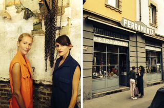 Two ladies, one in orange and one in navy dressed in jumpsuits next to a hardware store