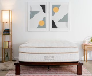 Saatva Classic Mattress in a bedroom against a white wall.