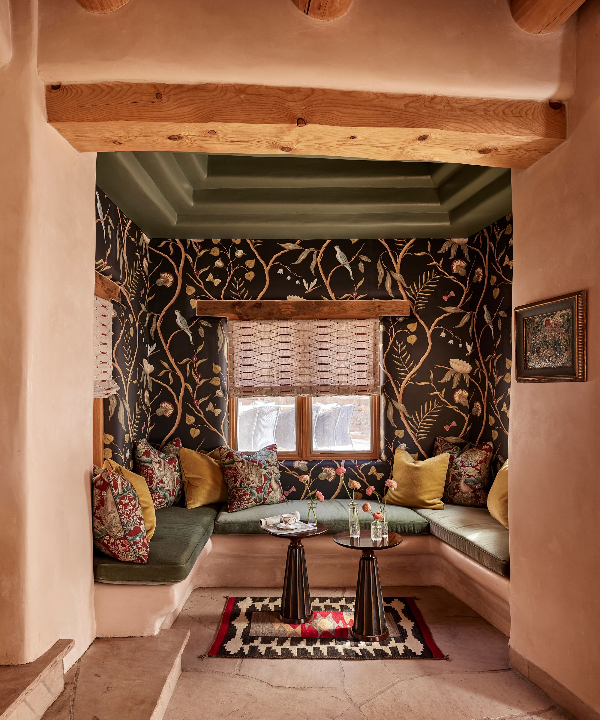 a banquette nook with botanical wallpaper, flagstone floors and chunky ceiling beams