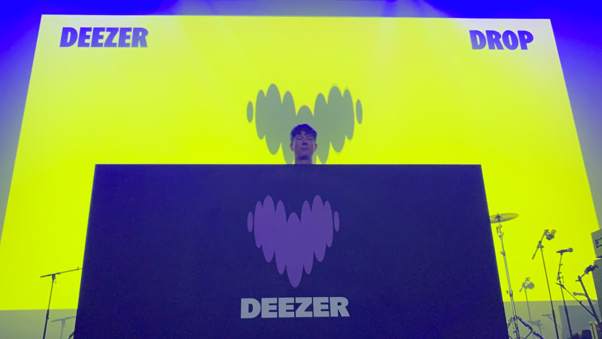  Диджей стоит за кабинкой с новым логотипом Deezer