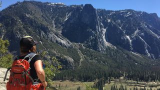 A hiker on retreat admires the view of Yosemite Valley
