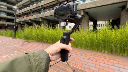 Hohem iSteady V3 gimbal being used to film a person on an iPhone