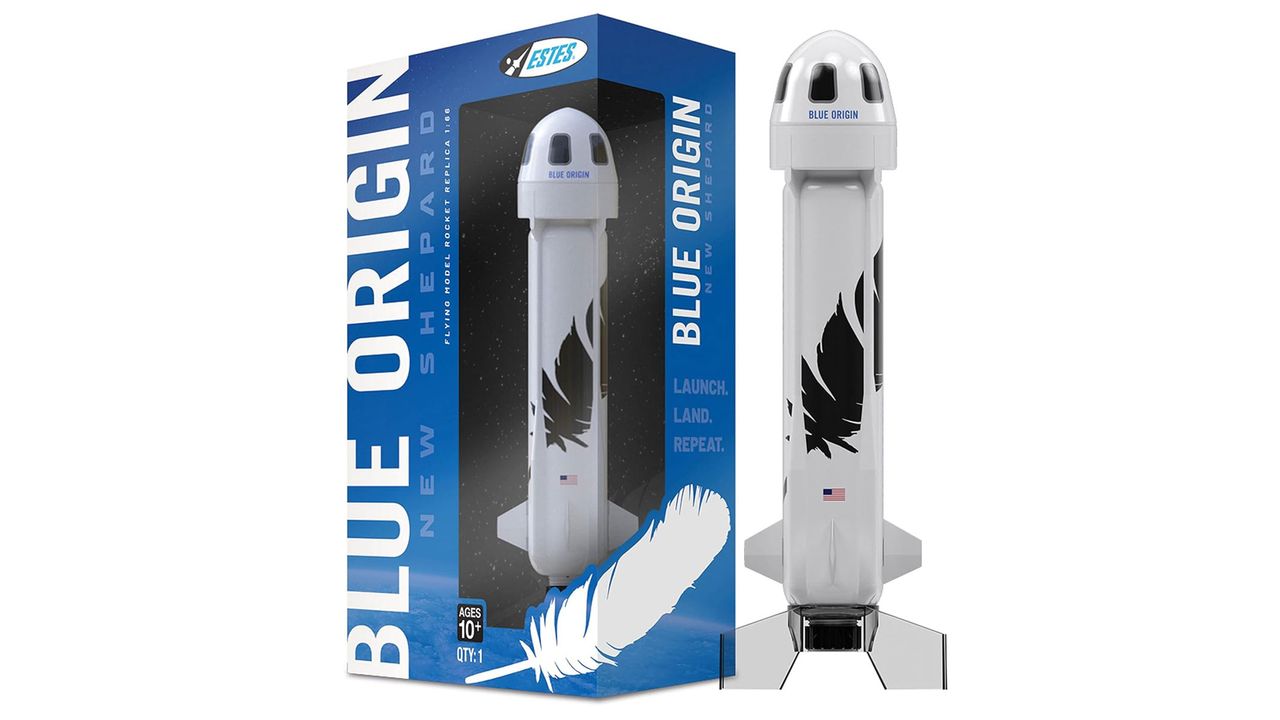 A white rocket with a black feather on the front and a rounded head is next to e a blue product box which reads "Blue Origin" all on a white background.