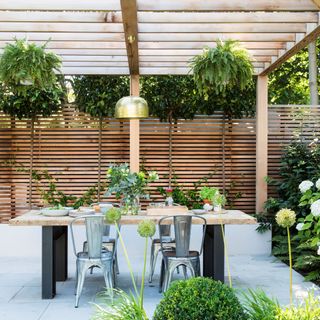 Patio with pergola and hanging planters with dining table and chairs