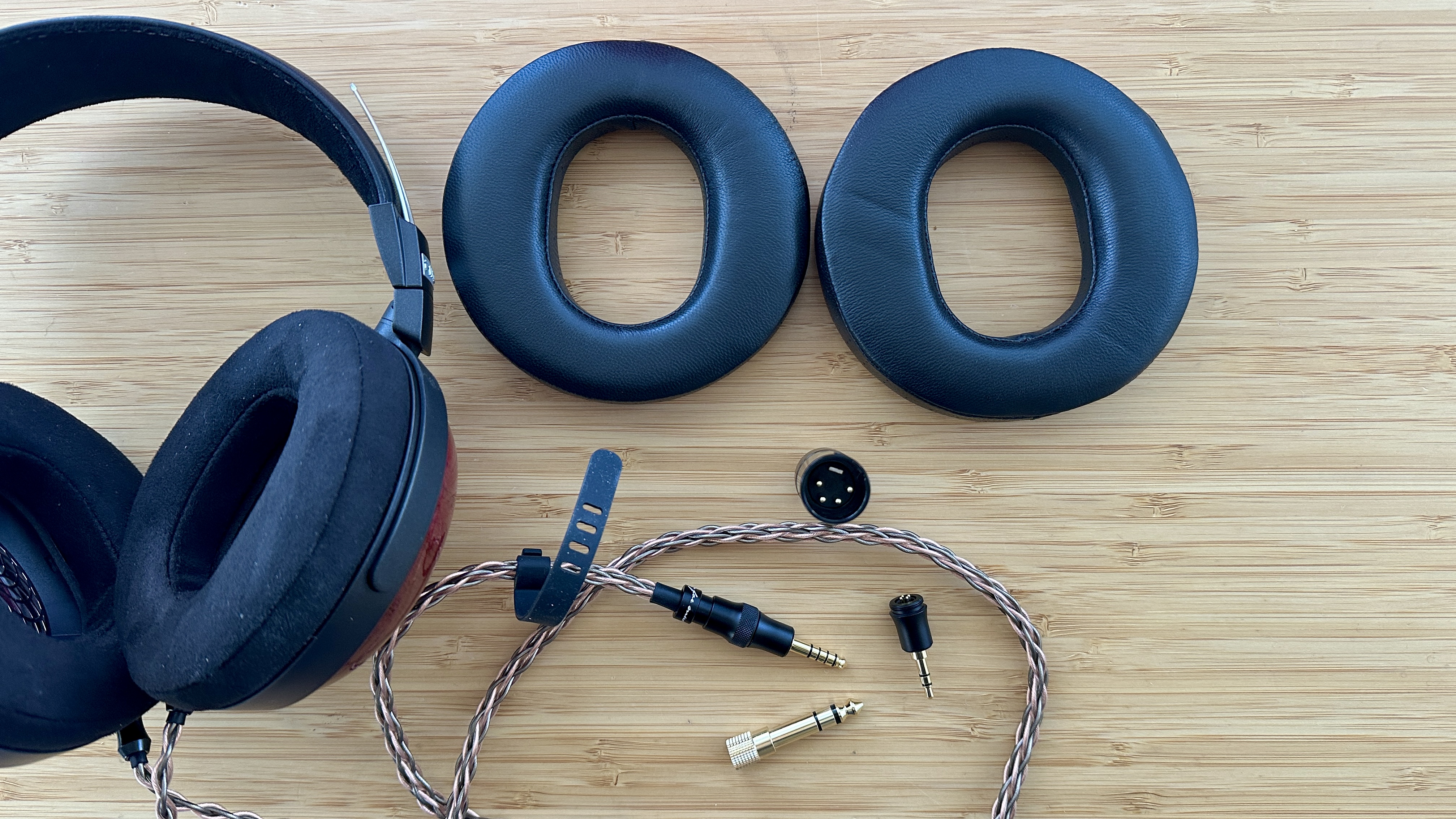 FiiO FT13 closed-back over-ear wired headphones, 1.5m cable, earpad options and various terminations, all on a wooden surface.