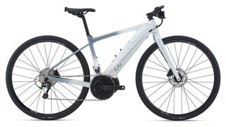 A side view of the Liv Thrive E+ electric fitness bike, with flat handlebars, a chunky downtube with integrated battery, and bulbous mid-drive motor