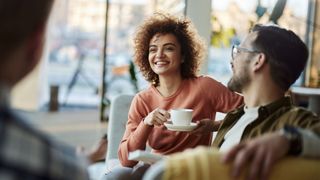 Woman laughing with coffee and friends in a group