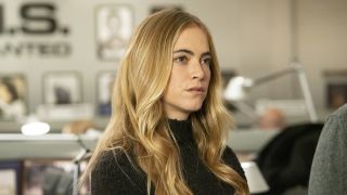 Emily Wickersham's Ellie Bishop standing in NCIS bullpen with a black, long-sleeved top