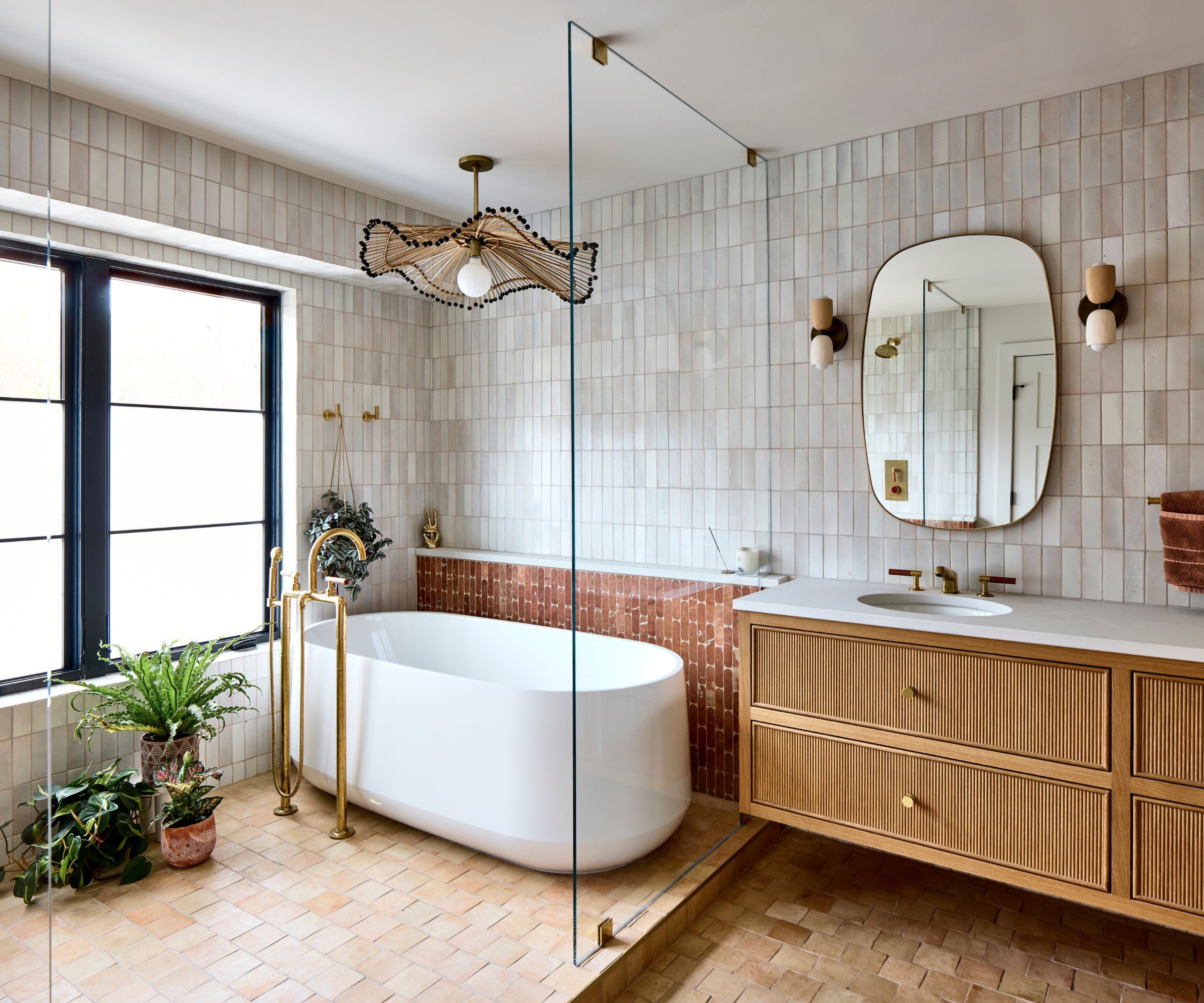 A large bathroom with a wooden vanity, a freestanding bath, and a large pendant light above