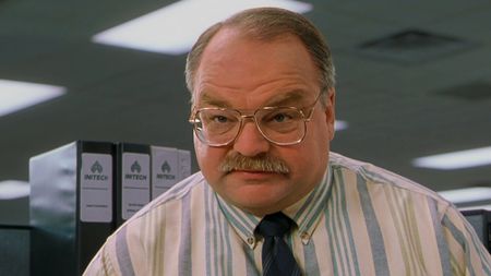 Richard Riehle, in a white, blue and yellow striped dress shirt and dark blue tie in Office Space (1999).