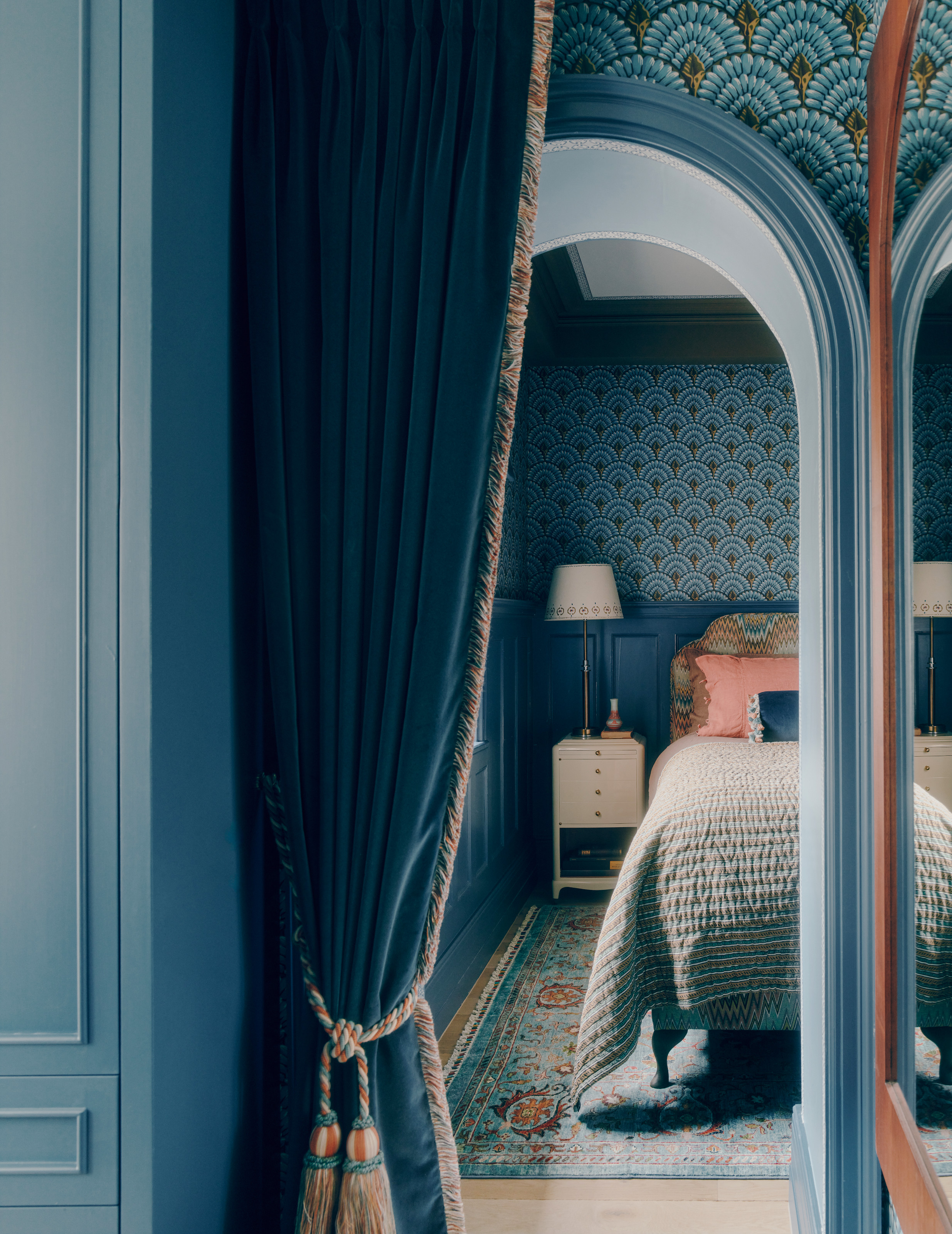Blue bedroom with arched opening, art deco style arch patterned wallaper and blue patterned rug