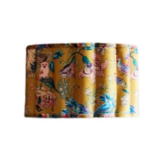 A yellow drum lampshade with red and blue flower illustrations decorating it